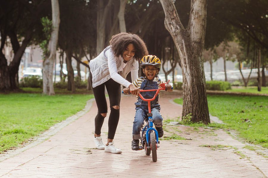 Personal Insurance - Mother and Son Riding a Bike Happily During a Rainy Summer